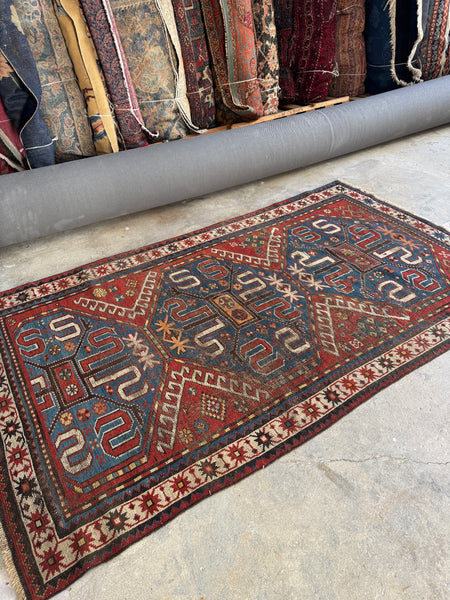 Worn wool Kazak rug with oxidized colors and soft texture.