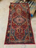 Antique Persian Heriz rug. Small hand knotted 1920s wool area rug with bold tribal geometry, animal motifs, and vivid vegetable-dyed colors.