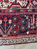 Handmade Persian Heriz rug. Vintage geometric area rug with brick red ground, floral borders, and bold architectural design.