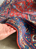 Antique red and blue Persian Malayer rug with scattered tribal symbols and soft worn in wool texture.