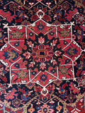 Vintage Persian Heriz rug with a kaleidoscopic coral medallion and deep red field.