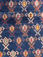 Close up view of Caucasian rug showing diagonal stripe effect created by tribal motifs.
