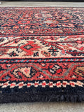 Authentic 1920s Persian wool rug detail view showing protective fringe covers stitched along the ends to prevent fraying.