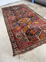 Diagonal shot showing rug’s pop of turmeric yellow and symbolic motifs.