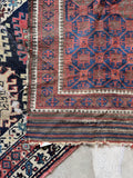 Small tribal Persian scatter rug with geometric motifs and a timeworn finish.