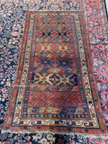 Worn geometric Persian Bidjar rug in brick red, blue, green and golden camel.