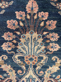 Early 1900s Persian rug detail highlighting the intricate floral medallion and organic texture.