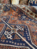 Hand knotted antique Shiraz rug with tribal symbolism and grounded nomadic energy.