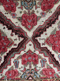 Antique Bakhtiari rug close-up showing sage green foliage and rose-toned floral clusters.