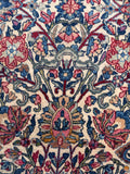 Floral detail highlighting intricate raspberry and coral blossoms with curling blue leaves.