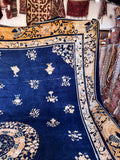 Blue and gold antique Chinese rug detail of the broad golden border featuring intricate stylized butterflies and scrolling vines.