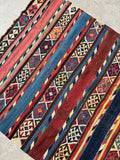 Flat weave area rug in red blue and yellow vegetable dyes for bohemian living room decor.