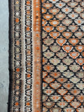 Flat weave runner with floral chain border resembling inkblots.