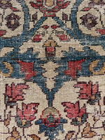 Close-up of a floral patterned fabric with red, blue, and ivory colors.