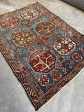 Antique Caucasian rug showing border bands and worn fringe edge.