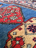 Antique Persian runner rug with repeating red medallions on a blue ground.