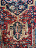 Antique Persian Heriz rug. Hand knotted tribal wool carpet with bold geometric motifs, vivid natural dyes, and a beautifully worn antique patina.