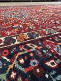 Antique Persian area rug. 1930s Heriz wool gallery rug with a crimson field, midnight blue border, and timeless heirloom craftsmanship.