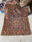Vintage 1920s Persian Gharajeh Heriz scatter rug with tribal scorpion motif and ram’s horn symbols, navy field, and brick red border.