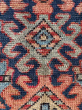 Close up of vintage Heriz rug with powerful tribal patterns, handwoven wool, navy and brick red tones, and symbolic scorpion design.