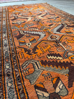 Close-up of Kurdish handwoven orange rug with tribal design.