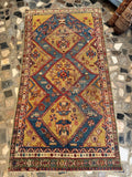 Persian tribal rug detail featuring colorful geometric borders and animal iconography on yellow wool.