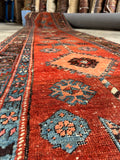 Antique tribal runner with scattered age-related wear and rich natural vegetable dyes.