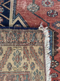 Underside view of a worn antique wool area rug featuring weave texture.