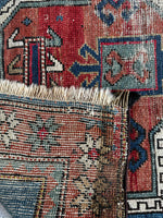 Underside view of antique wool rug with bold tribal medallions and protective symbols.