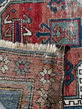 Underside view of antique wool rug with bold tribal medallions and protective symbols.