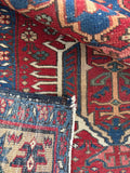 Underside view of antique Persian Heriz rug with low pile, tribal symbols, and warm old world character.