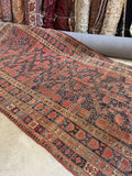 Handwoven antique Persian rug with natural dyes and repeating tribal diamond design.