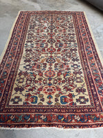 Ivory ground Persian rug measuring just under 4x7 feet.