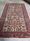 Ivory ground Persian rug measuring just under 4x7 feet.