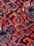 Close up detail of handwoven Persian rug showing saturated vegetable dyed wool and playful boteh (paisley) motifs.
