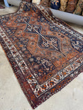 Early 1900s Persian Shiraz rug with warm rust ground and geometric medallions.