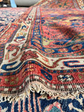 Red, blue, and green geometric Bidjar rug with bold stepped tribal patterns.