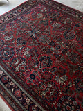 Brick red field with scattered floral sprays on vintage rug.