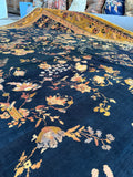 Allover floral pattern on a deep blue antique rug with glowing yellow tones.