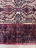 Warm ivory antique Persian area rug close-up shot focused on the raspberry-mauve accents along the outer guard edge.