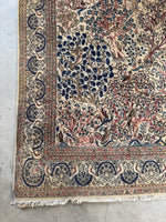 Ivory Persian rug featuring florals, birds, and ribbon motif border.
