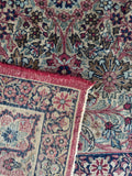 Low pile antique Persian rug featuring intricate floral sprays and navy border bands.