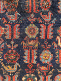 Close up of handwoven Persian scatter rug with an irregular shape and tribal animal design.