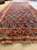 Close-up of antique Persian Kurd runner with midnight blue background and paisley motifs.
