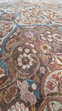 Curving vines and rose-colored flowers fill the ivory border of a large antique Persian rug.