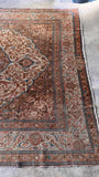 Natural light highlighting the honeyed brown, soft ivory, and dusty pink tones of a large vintage rug.