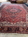 Large red Persian Heriz rug with navy blue accents and ivory corner spandrels.