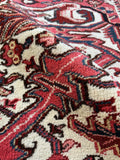 Close up of vintage Persian Heriz rug with deep red tones and striking ivory contrast.