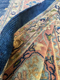 Antique floral Turkish rug with soft blush, ivory, sage, and powder blue accents on navy.