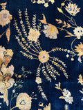 Closeup of antique Laristan rug with floral motifs on a midnight blue field.